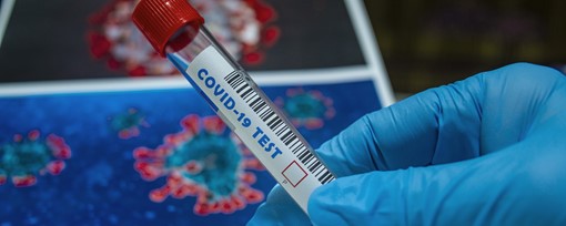 A gloved hand holding a COVID-19 test tube.