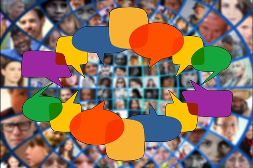 A circle of coloured speech bubbles on an out of focus background of people's faces.    
