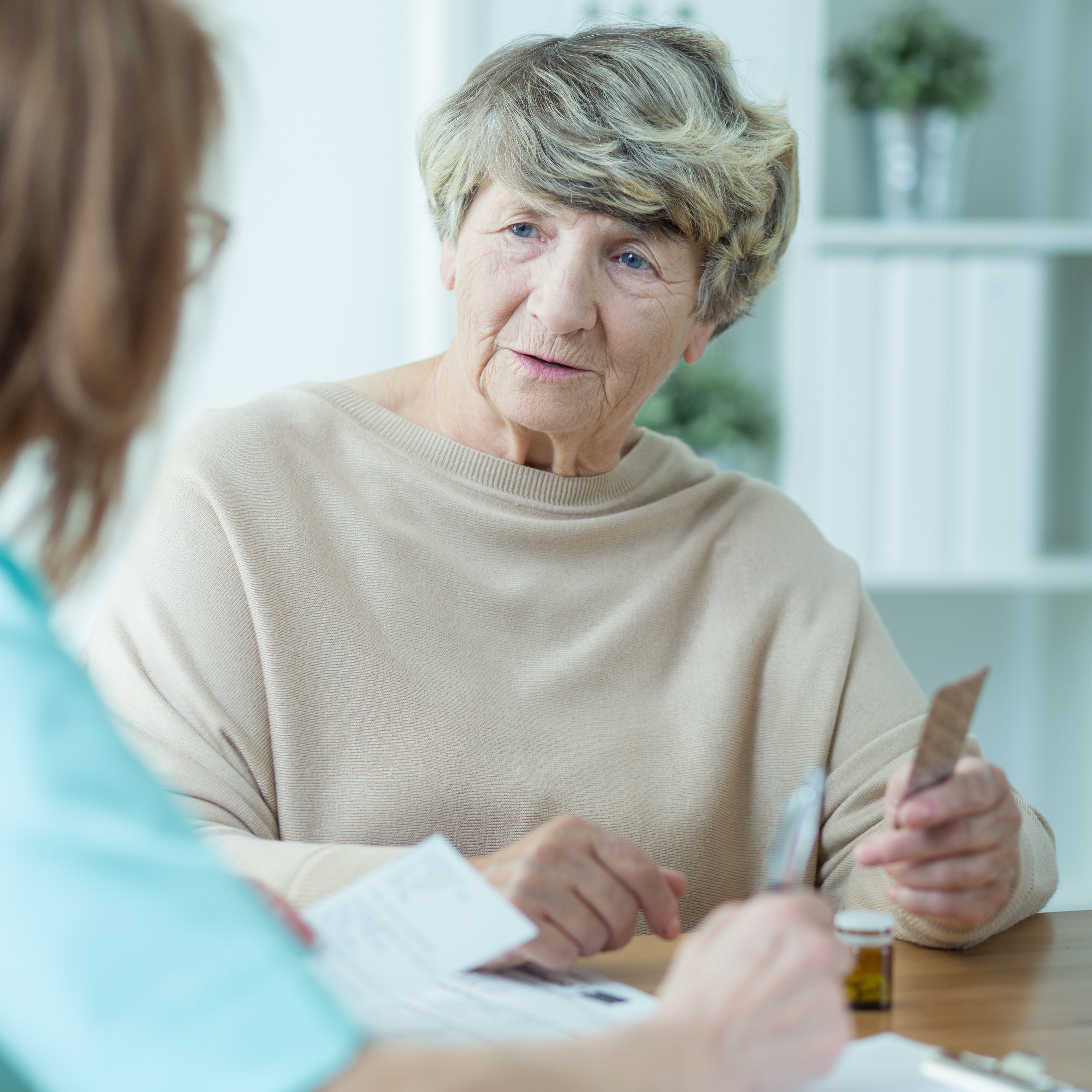 An older person and a nurse discuss medication