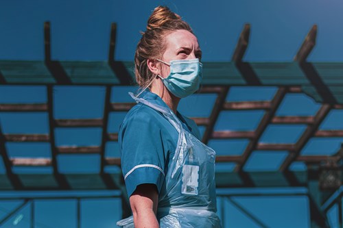 A health care worker wearing a face mask, gloves and apron. 
